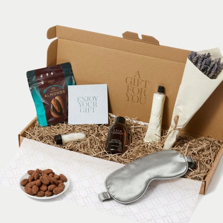 M&S Hampers Pamper Night In Letterbox Gift. The box is open revealing the contents including a lavender posy, a silver eye mask and a dish of almonds.