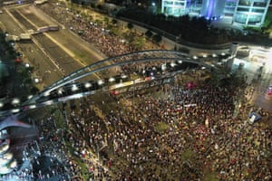 An overhead view of people gathering at night on a road by a bridge