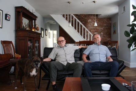 Two men sit on a black couch in a house