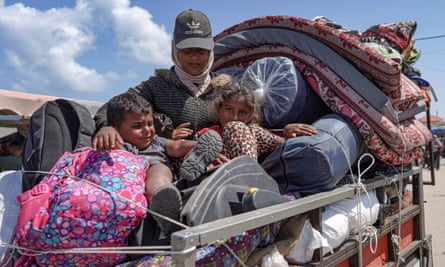 A Palestinian woman and children who fled Rafah in the southern Gaza Strip ride with their belongings in the back of a truck, as they arrive to take shelter in Deir el-Balah in the central part of the Palestinian territory.
