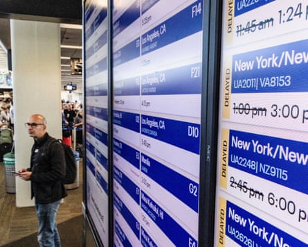 A passenger stands by a screen showing delayed flights