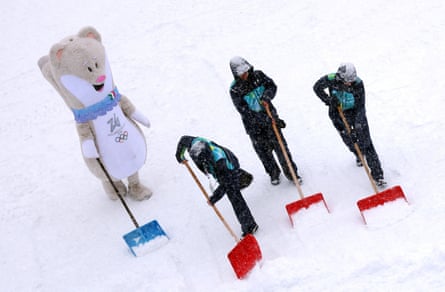 The Winter Olympic stoat mascot, Tina, helps out with shovelling snow amid heavy snowfall before the men’s slalom