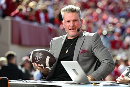 A sports announcer holds a football while wearing a headset microphone