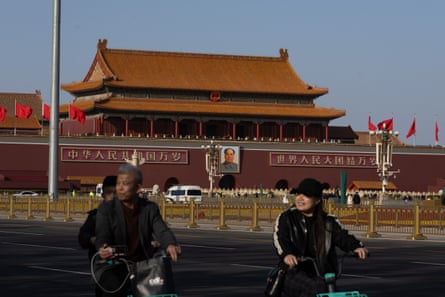 People ride motorbikes past the entrance gate to the Forbidden City in Tiananmen Square