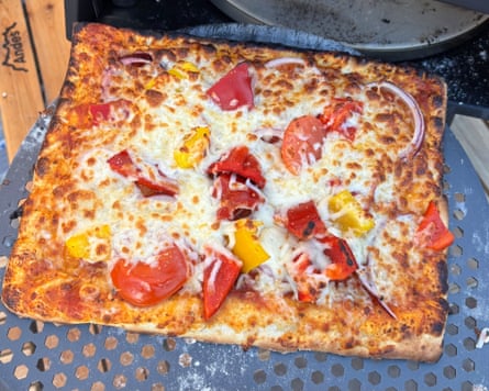 Slice of vegetarian pizza with tomatoes and peppers just removed from the ProCook Outdoor Pizza Oven.