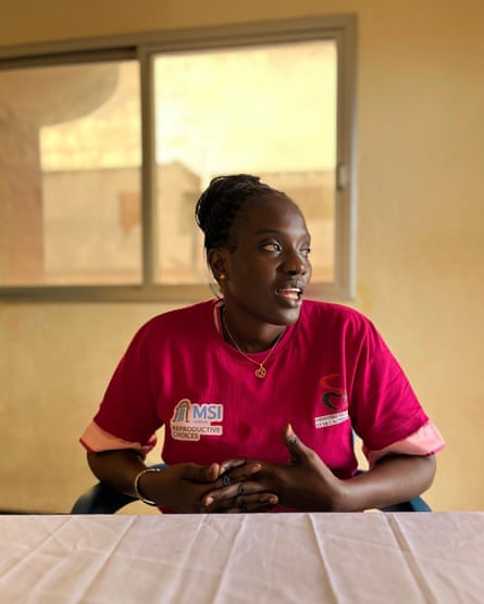 A black woman in a pink shirt sitting at a table