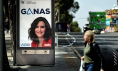 A woman walks past an electoral campaign poster of PP candidate Isabel Diaz Ayuso, in Madrid.