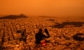 A couple sit on Tourkovounia hill, as southerly winds carry waves of Saharan dust, in Athens