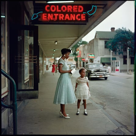 A woman and girl standing outside a department store in Mobile, Alabama, with a “Colored Entrance” sign above them, in 1956
