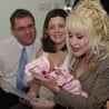 Dolly Parton holds newborn Emma wrapped in pink, beside her seated parents