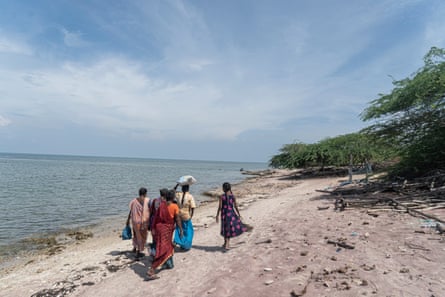 A group of women walk along the shore.