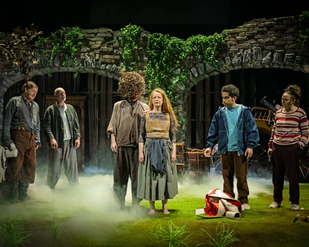 Actors from the play Refuge stand on a misty stage before stone archways