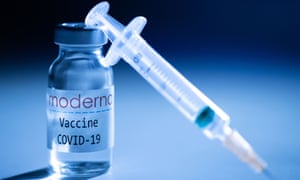 A syringe and a vaccine vial bearing the logo of US biotech firm Moderna.