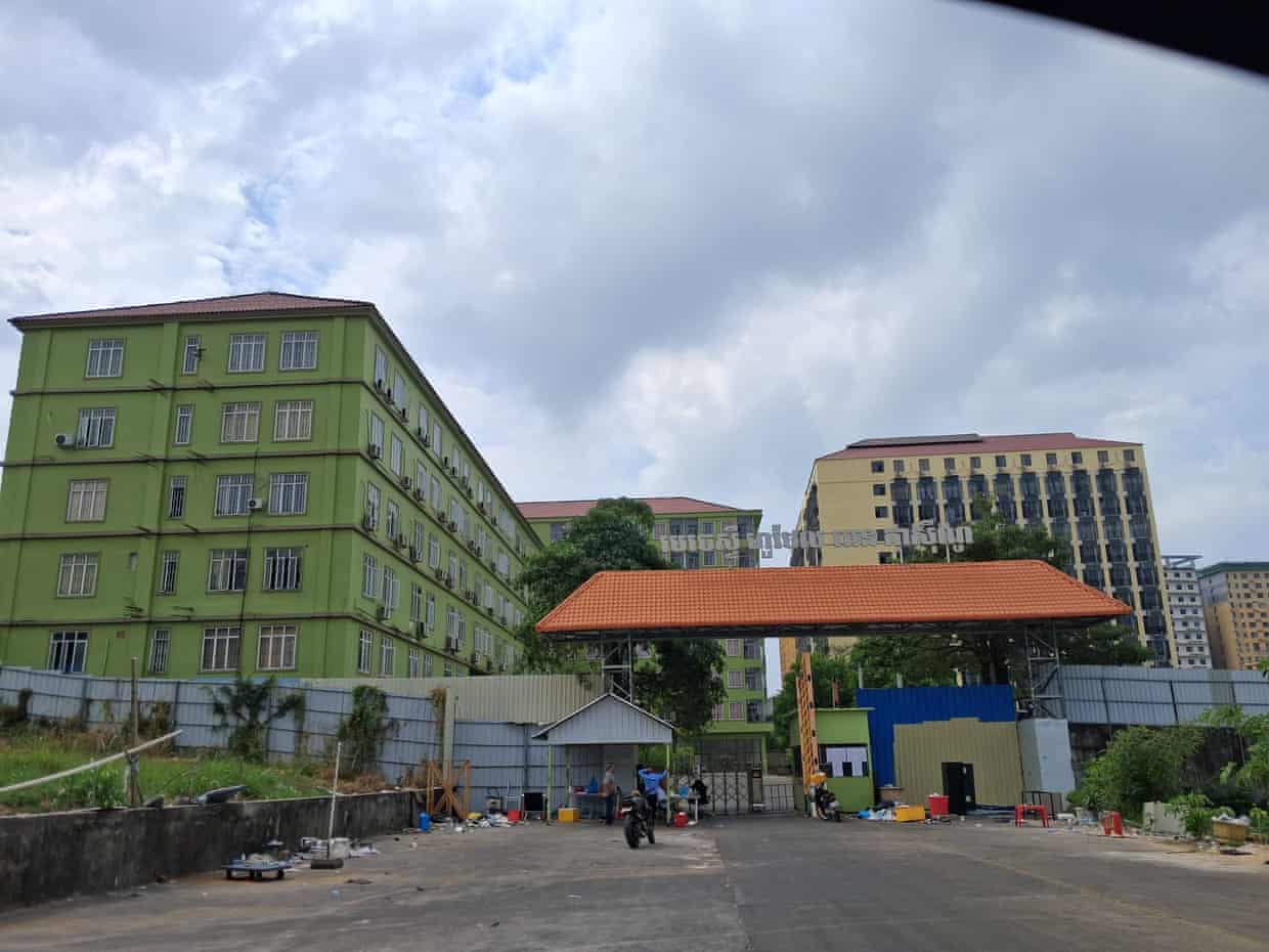 A multistorey green building with a surrounding compound.