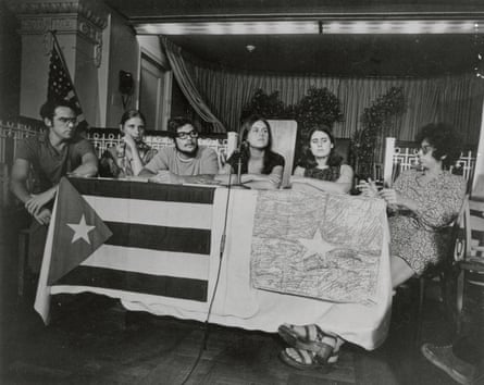 six people sit behind a table with two flags apparently made out of paper - they appear to be cuba’s and vietnam’s - in a black and white photo