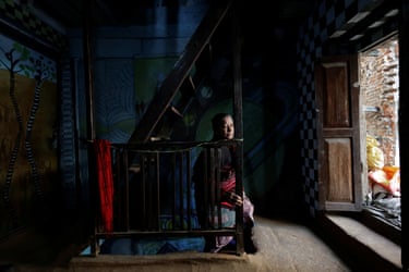 Lata Maya Maharjan climbs the stairs in her home, while her face gets caught in the light