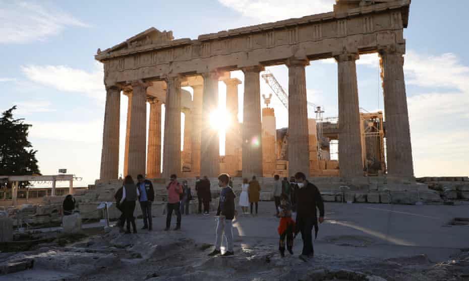 People wearing protective face masks make their way next to the Parthenon temple atop the Acropolis hill, in Athens.