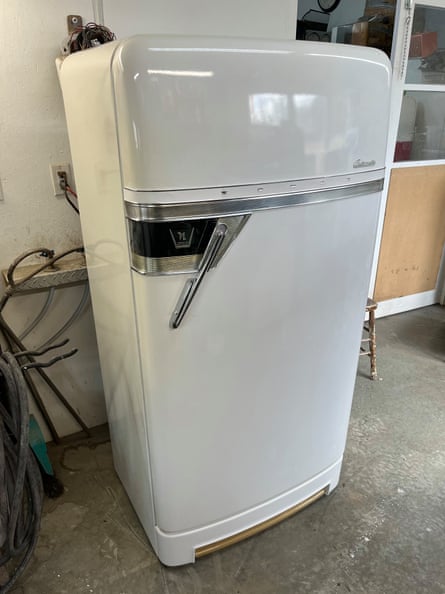 A shiny white fridge with rounded corners at the top and large metal handle