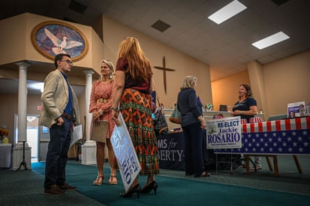 some people in a church with signs saying re-elect Jackie Rosario