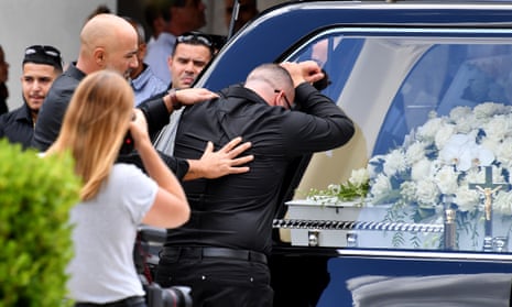 Simon Tadros, husband of helicopter crash victim Vanessa Tadros, is consoled as her casket is placed in the hearse.