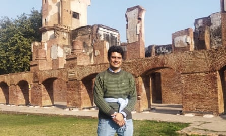 man standing in front of some red brick ruins