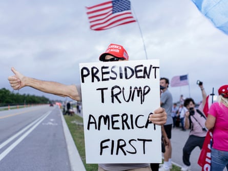man holds sign that says ‘president trump - america first’