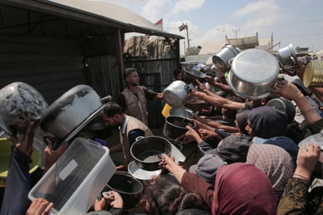 Palestinians hold out their empty pots in front of a charity kitchen in Khan Yunis in the southern Gaza Strip on August 21, 2025.
