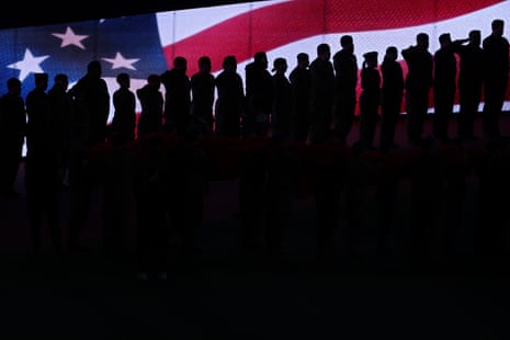 Members of the military salute in front of the American flag during the singing of the national anthem prior to Game 7.