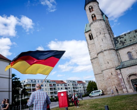 A man carries a German flag through Magdeburg city centre