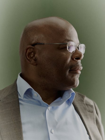 A man wearing glasses and a button-down poses for a portrait