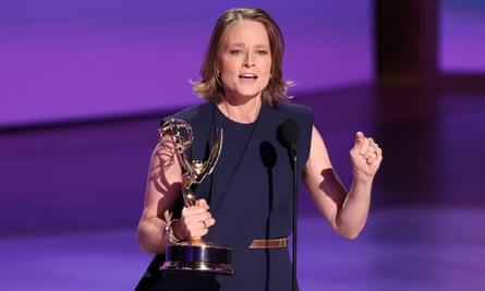 woman wearing blue dress holds gold statue