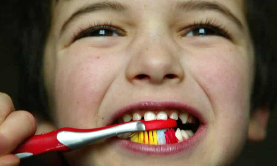 Close up of a young boy cleaning his teeth with a multi-coloured toothbrush