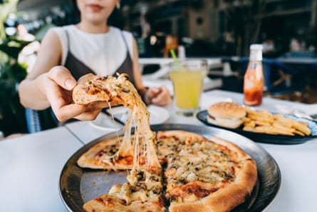 Woman getting a slice of freshly made cheesy pizza