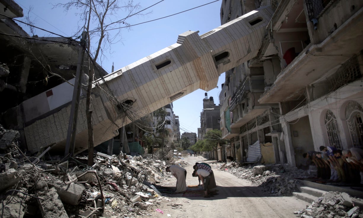 Palestinians attend Friday noon prayer beneath the fallen minaret during the 2014 war.