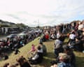 A large crowd gathers on a grassy slope on Garvaghy Road, watching a performance below