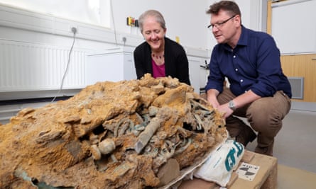 Dr Emily Williams and Prof Tom Moore crouch in front of a pile of tangled artefacts