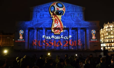 People watch as the facade of the Bolshoi Theatre is illuminated with the official emblem of the 2018 World Cup, which will be held in Russia