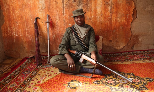 Aisha Gombi Bakari sits with her rifle.