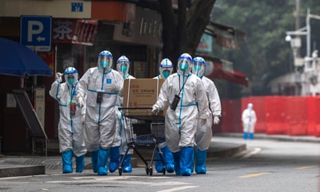 Workers in personal protective equipment walk through a residential area in Guangzhou under Covid lockdown.