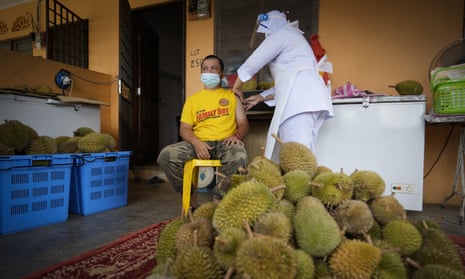 A nurse administers a Pfizer vaccine to a durian fruit vendor at his house in rural Malaysia