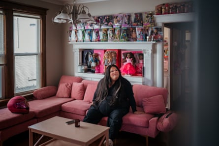 Jools Lebron in her loumge sitting on a pink sofa surrounded by her doll collections