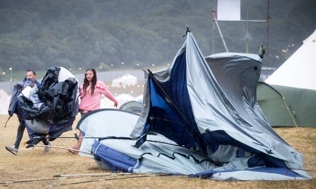 Festivalgoers pass a collapsed tent at Lulworth Castle in Dorset during Camp Bestival.