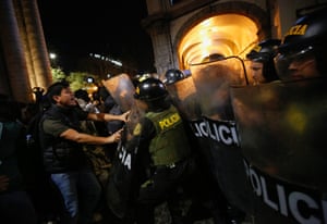 Police behind riot shields confront a protester
