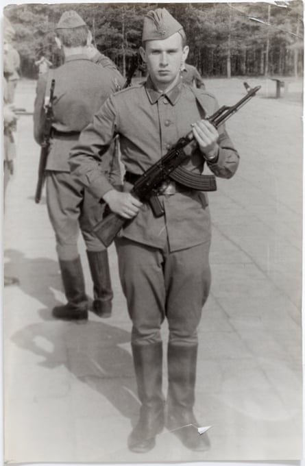 An old full-length black and white picture of Karpichkov in military uniform holding a rifle, looking at the camera