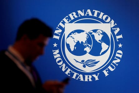 A participant stands near a logo of the IMF