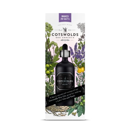 A bottle of Cotswolds dry gin essence in a box. The box has is decorated with floral illustrations and features a die cut bottle shape in the centre so you can see the black bottle.