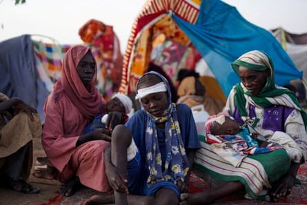The grandmother of Ikram Abdelhameed looks on next to her family while sitting at a camp for displaced people who fled from al-Fashir to Tawila.