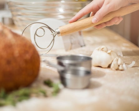 Hand holds a bread dough whisk in a kitchen.