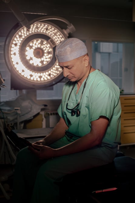 Shehan Hettiaratchy looking at his phone with a large light behind h,