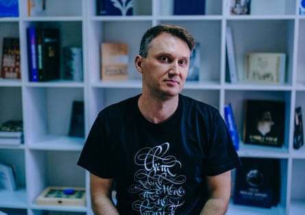 Oleksandr Savchuk sitting in front of a sparse bookcase